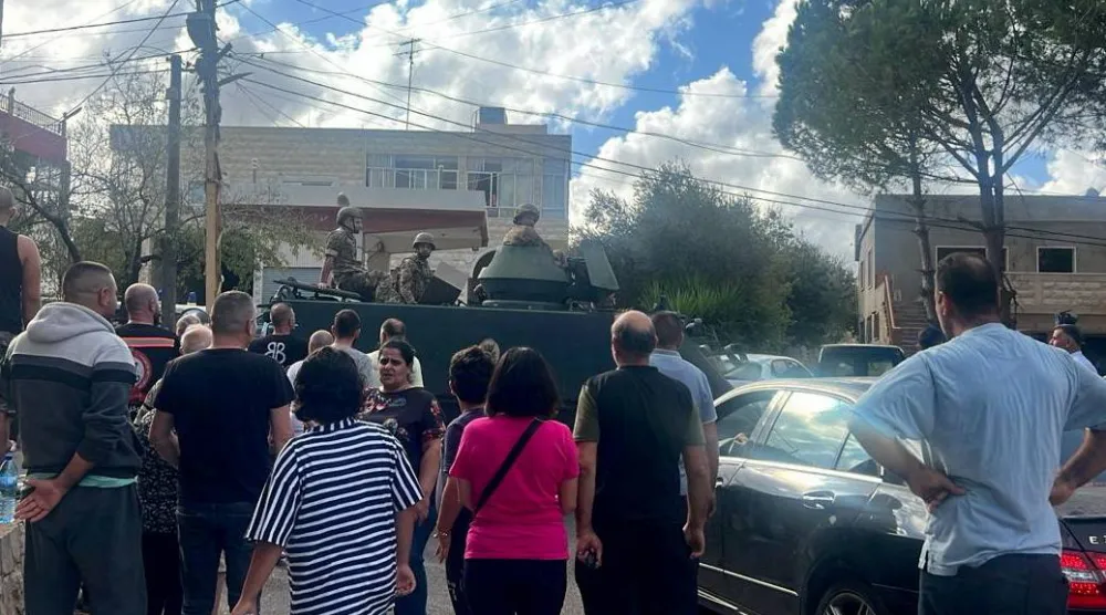 لبنانيون يتجمعون أمام دورية للجيش قرب دير في بلدة رميش بعدما غادروا قرية عين إبل يوم 1 أكتوبر 2024 خلال الحرب السابقة (رويترز)