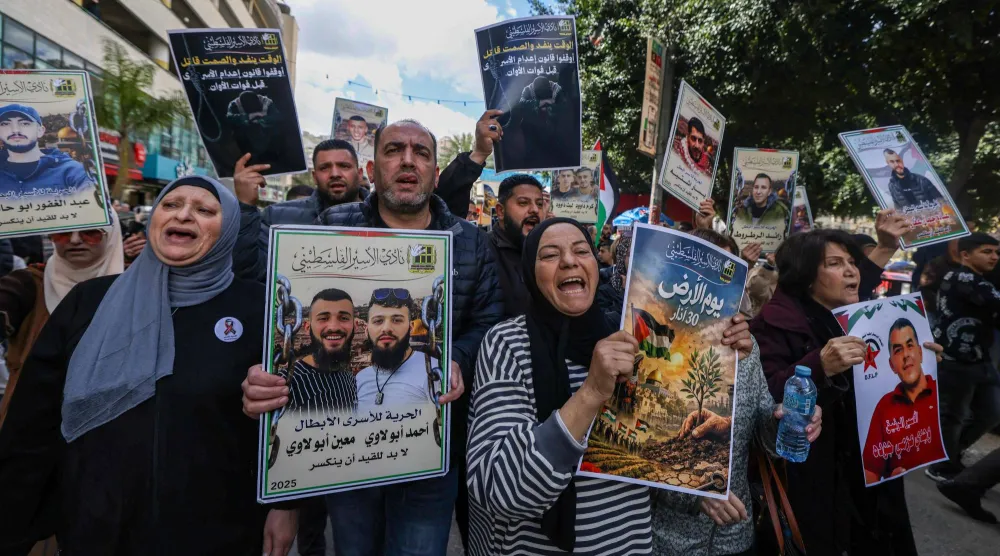 أقارب الأسرى الفلسطينيين يحملون لافتات ويهتفون بشعارات خلال مسيرة في مدينة نابلس بالضفة الغربية (أ.ف.ب)