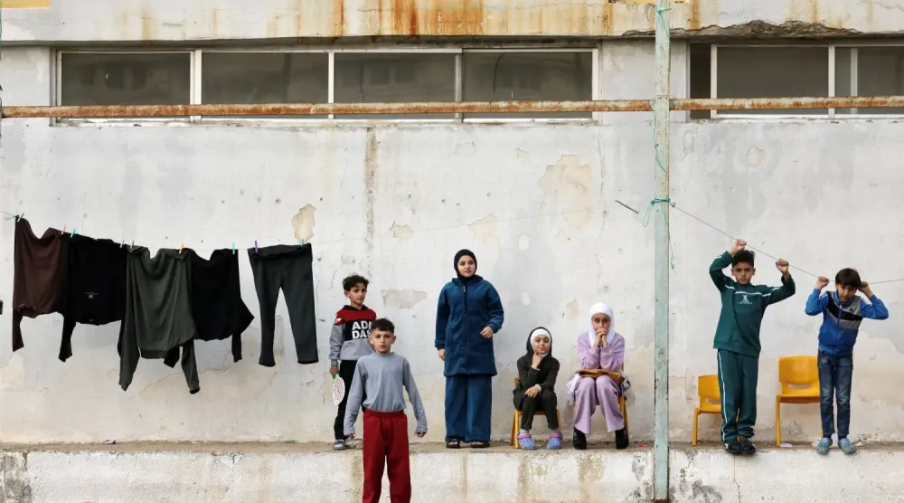 İsrail'in Lübnan'a yönelik saldırıları sırasında geçici sığınak olarak kullanılan ortaokulun bahçesinde bir grup yerinden edilmiş çocuk (Reuters)