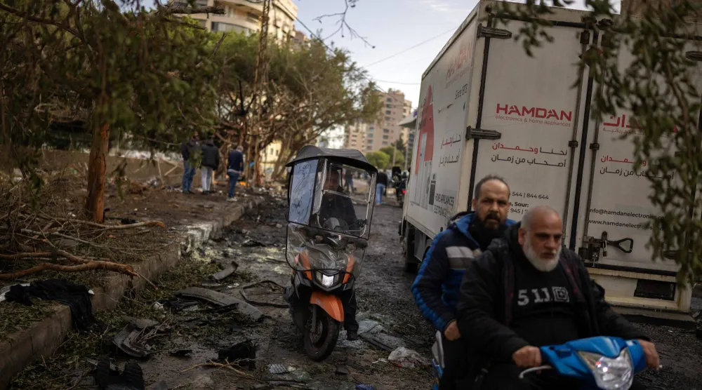 يمرّ أشخاص على دراجاتٍ نارية صغيرة بموقع سقوط غارة إسرائيلية في بيروت (رويترز)