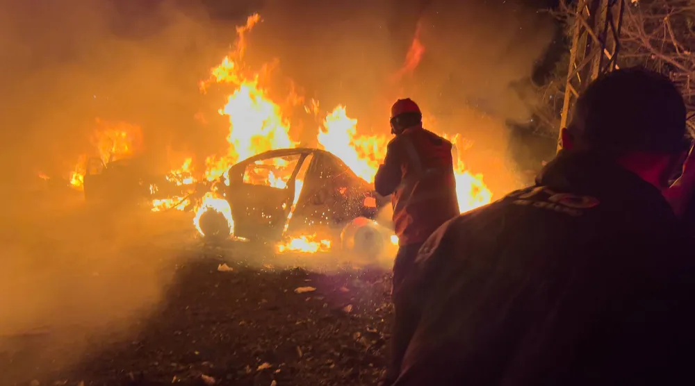 عمال إنقاذ يتفقدون موقع الضربة الإسرائيلية وسط احتراق عدد من السيارات ببيروت (أ.ب)