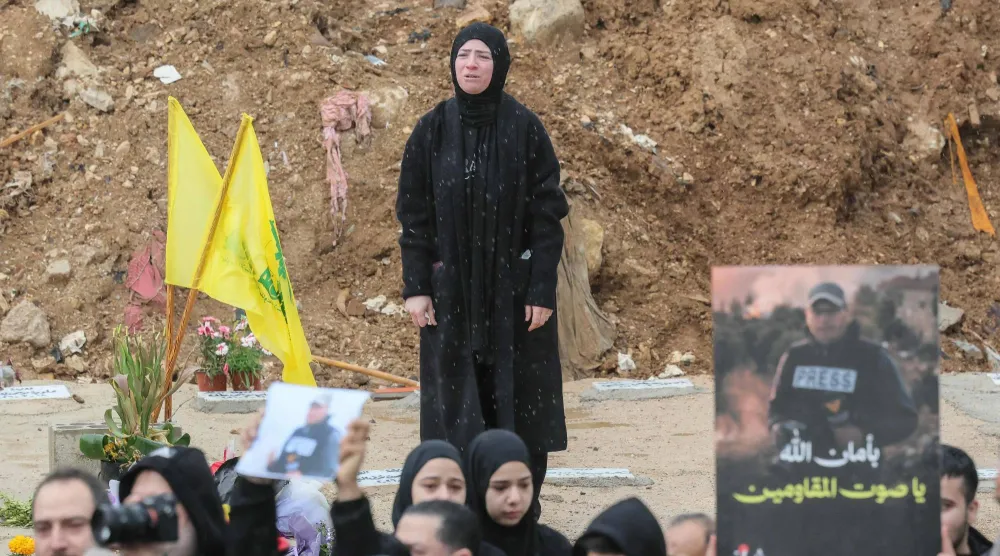 سيدة تشارك في تشييع صحافيين قتلوا بغارة إسرائيلية بجنوب لبنان (أ.ف.ب)