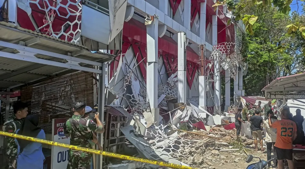 أشخاص يتفقدون مبنى تضرر جراء زلزال ضرب مانادو في شمال سولاويزي في إندونيسيا (إ.ب.أ)