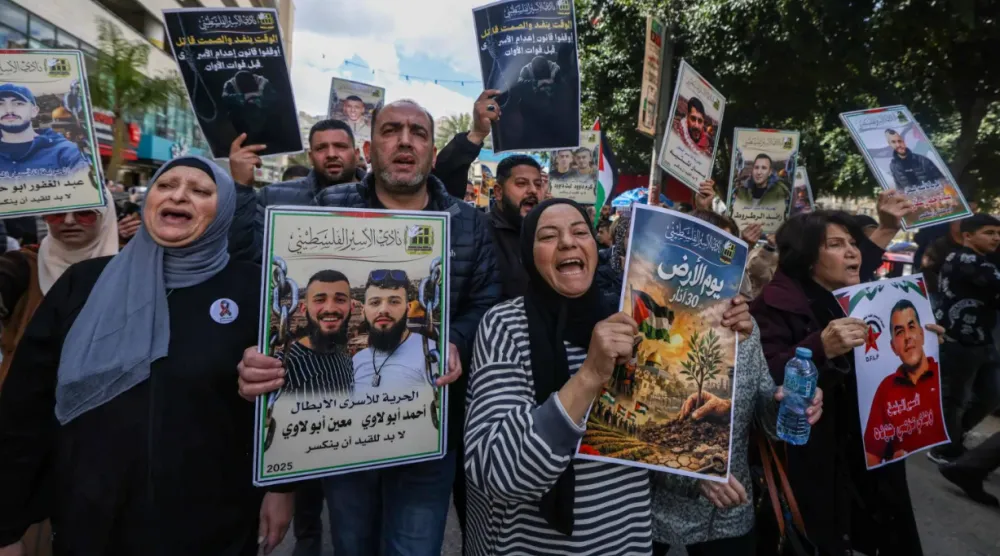 أقارب الأسرى الفلسطينيين يحملون لافتات ويهتفون بشعارات خلال مسيرة في مدينة نابلس بالضفة الغربية (أ.ف.ب)