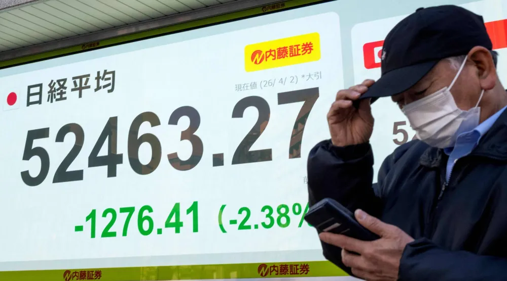 رجل يقف أمام شاشة تعرض حركة الأسهم في وسط العاصمة اليابانية طوكيو (أ.ف.ب)