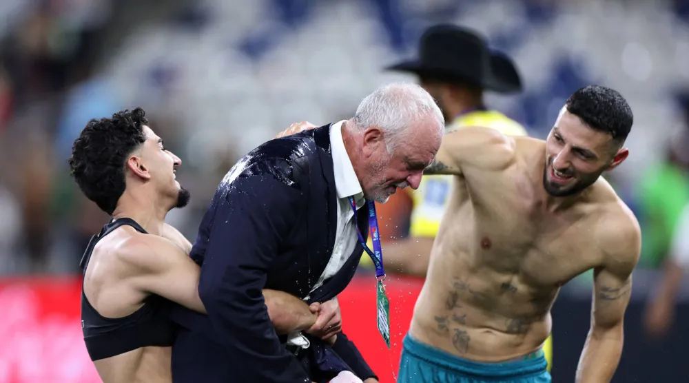 احتفل مدرب المنتخب العراقي غراهام أرنولد بالتأهل على أكتاف اللاعبين (أ.ف.ب)