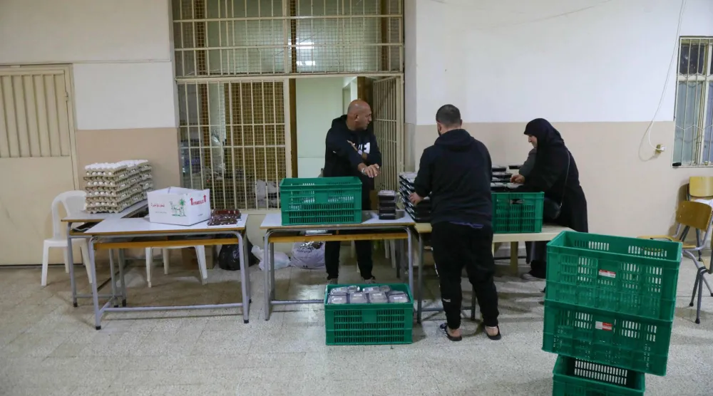 عاملون ومتطوعون في مبادرة لمنظمة غير حكومية يوزعون وجبات الطعام بمدرسة تؤوي نازحين في سن الفيل شرق بيروت 28 مارس 2026 (أ.ف.ب)