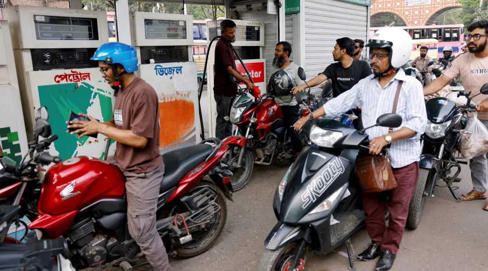 سائقو الدراجات النارية يصطفون للتزود بالوقود في محطة وقود في دكا (رويترز)