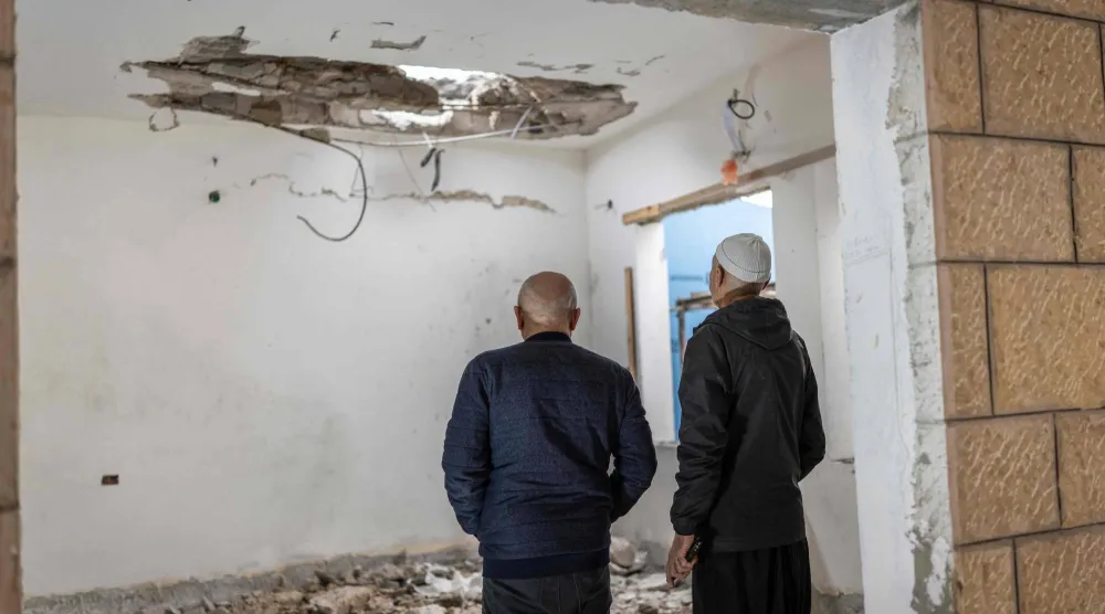 شخصان من المكون الدرزي يعاينان موقع سقوط صاروخ أطلقه «حزب الله» في مدينة شفا عامر بشمال إسرائيل (أ.ف.ب)