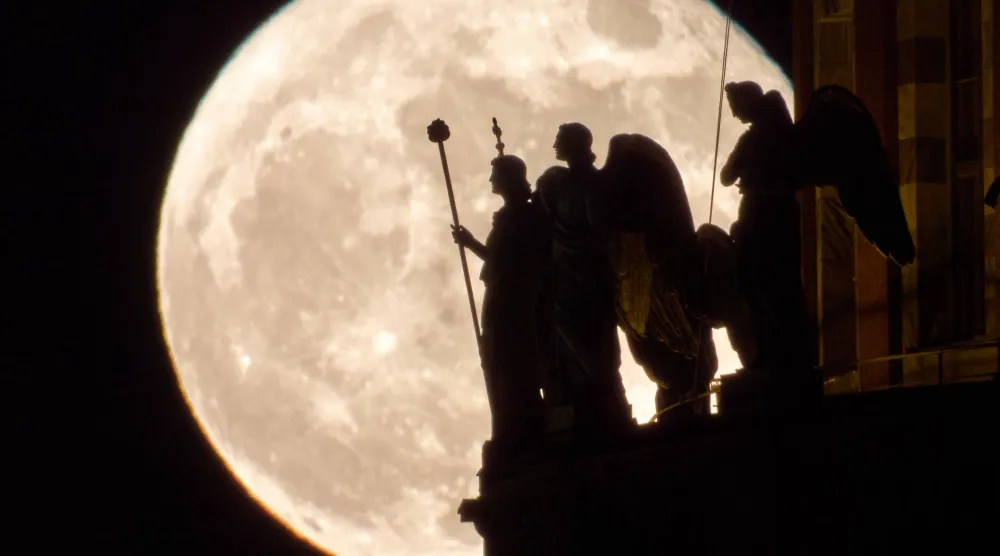 يرتفع القمر بدراً خلف تماثيل الملائكة في كاتدرائية القديس إسحاق في سانت بطرسبرغ، روسيا (أ.ب)