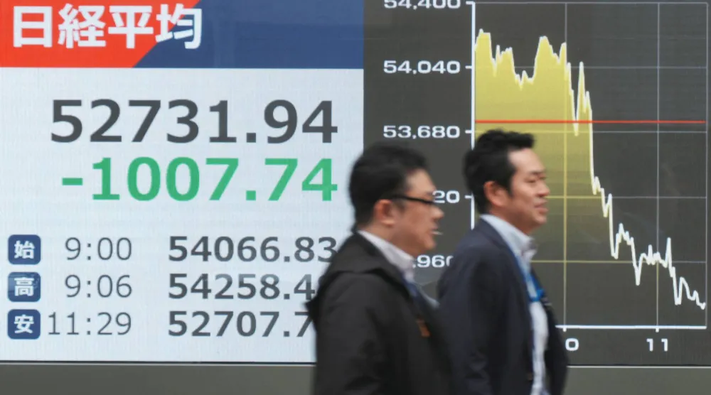 رجلان يمران أمام شاشة إلكترونية تعرض حركة الأسهم في وسط العاصمة اليابانية طوكيو (أ.ف.ب)