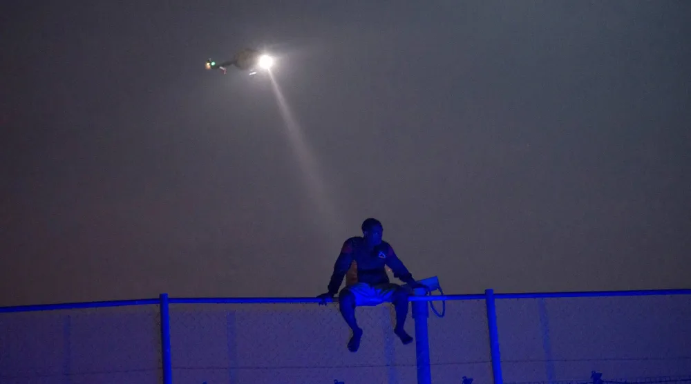 مهاجر أفريقي يحاول تسلق الجدار الفاصل بين مليلية المحتلة وإسبانيا (رويترز)