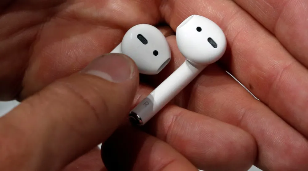 شخص يحمل سماعات أذن «إيربودز» (رويترز)