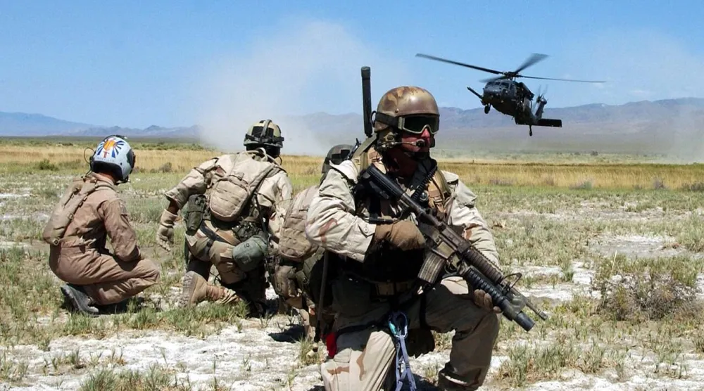 عناصر الإنقاذ المظلي التابعون لسلاح الجو الأميركي بالإضافة إلى شخص يُحاكي عملية «النجاة» يراقبون هبوط مروحية بوصف ذلك جزءاً من عملية تدريبية للجيش (أرشيفية - سلاح الجو الأميركي)