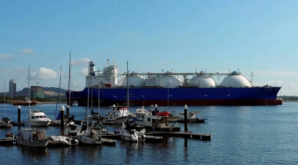 ناقلة غاز طبيعي مسال تمر بقوارب على طول ساحل سنغافورة (رويترز)