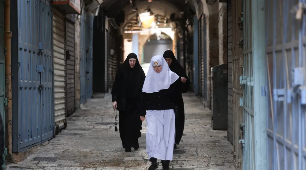 مصلون مسيحيون يسيرون بالقرب من كنيسة القيامة المغلقة بعد إلغاء موكب «أحد الشعانين» التقليدي من جبل الزيتون في البلدة القديمة بالقدس (رويترز)