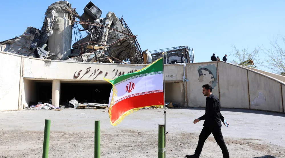 رجل يسير بجوار علم إيران في طهران (إ.ب.أ)