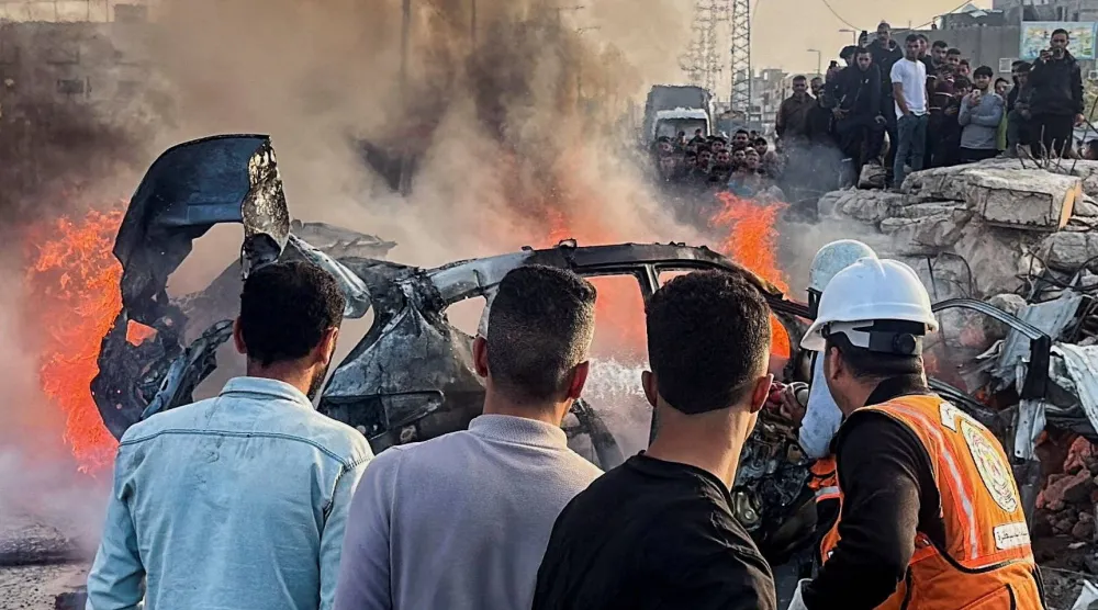 فلسطينيون يتفقدون موقعاً قال مسعفون إنه شهد غارة جوية إسرائيلية استهدفت سيارة قرب مدخل بلدة زويدا وسط غزة (رويترز)