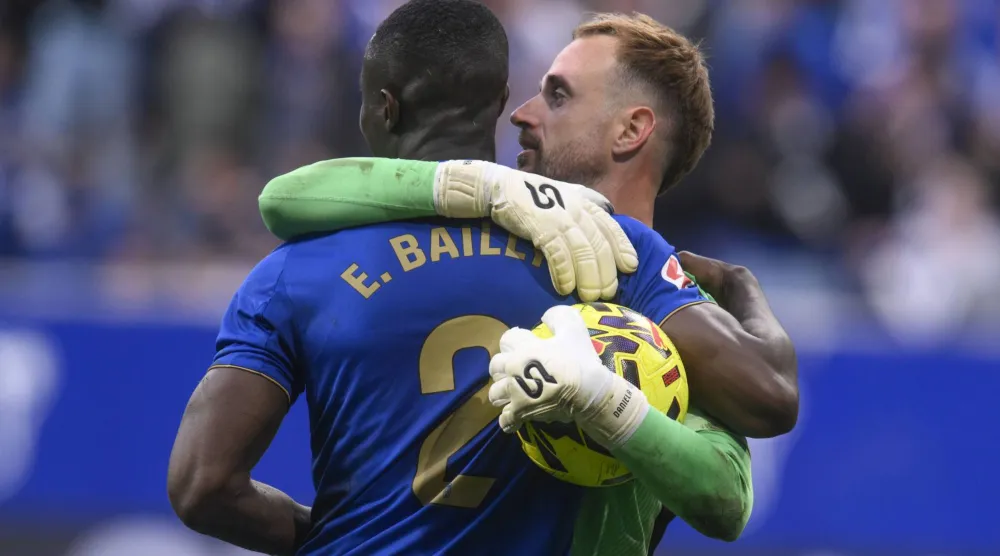 إيريك بايلي لاعب أوفييدو يحتفل مع حارس مرماه آرون سكانديل بالفوز على إشبيلية (إ.ب.أ)