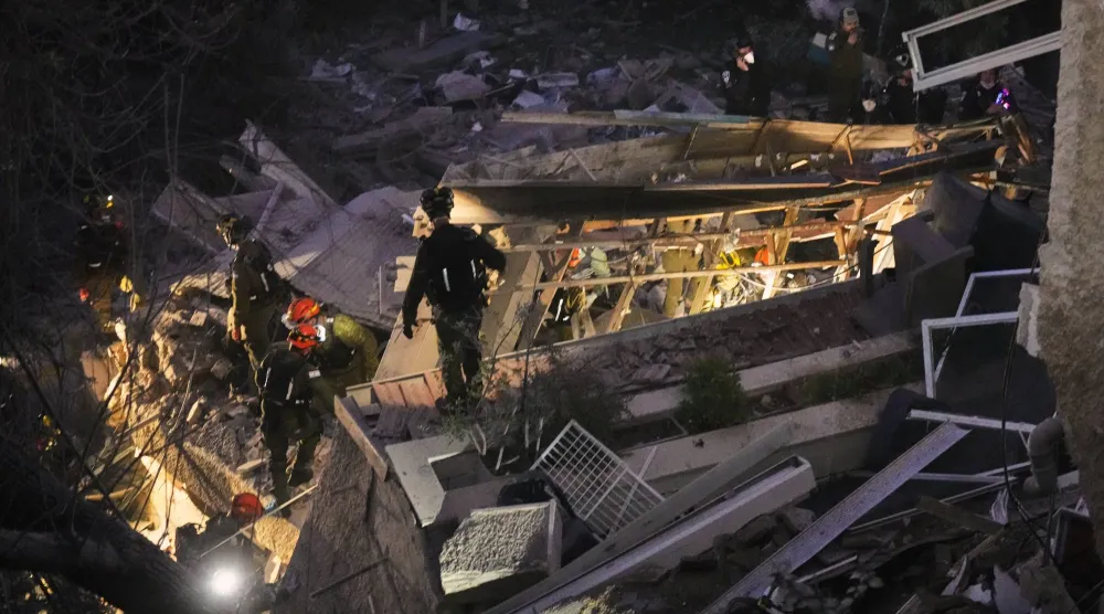 عناصر أمن وإنقاذ يعملون وسط أنقاض بناية سكنية استهدفها صاروخ إيراني في حيفا أمس (أ.ب)