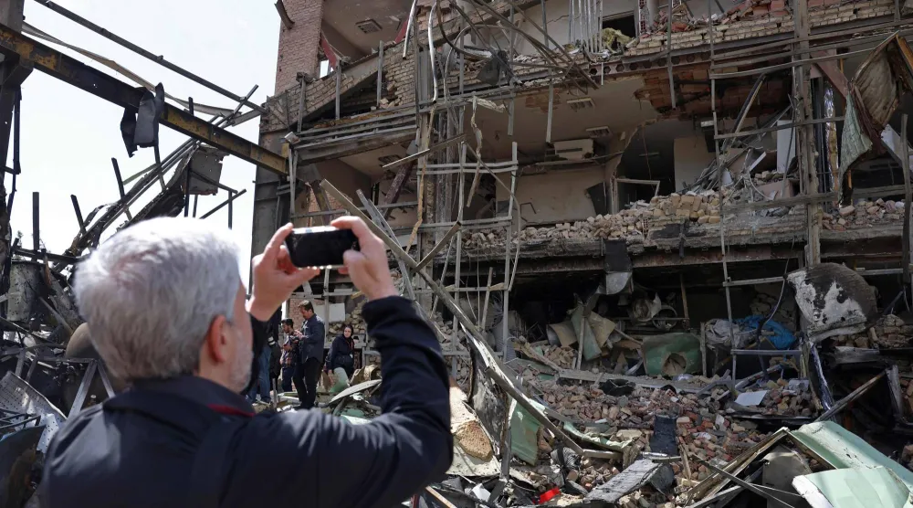 رجل يلتقط صوراً لمبنى جامعة شهيد بهشتي المتضرر عقب غارة جوية في طهران (ا.ف.ب)