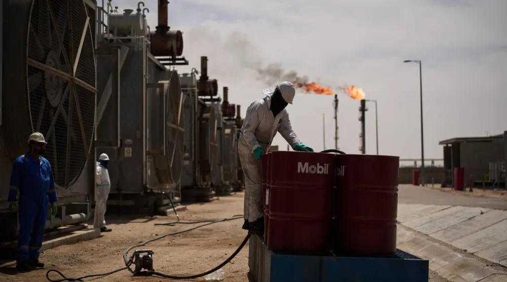 عامل يجمع زيت المحرك أثناء عمله في محطة إزالة الغازات في حقل الزبير النفطي بالقرب من البصرة (أ.ب)