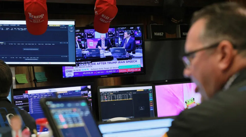 متداول يتابع الأخبار المالية على الشاشات في بورصة نيويورك (أ.ف.ب)