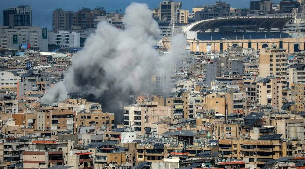 Smoke rises from the site of an Israeli strike in Beirut's southern suburbs, near Camille Chamoun Sports City stadium (R), on April 6, 2026. (AFP)