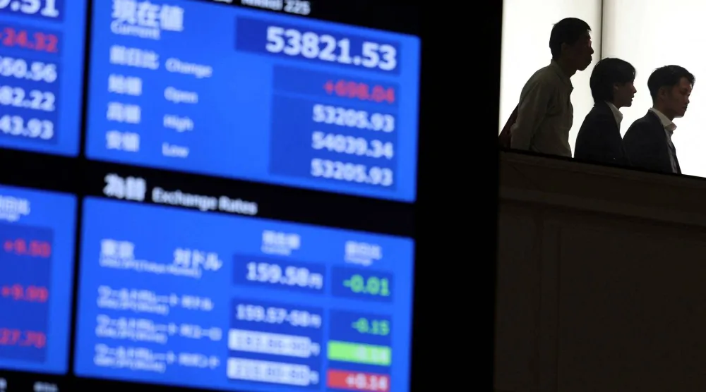 يتجول الزوار بالقرب من شاشات تعرض معلومات عن الأسهم ببورصة طوكيو (رويترز)