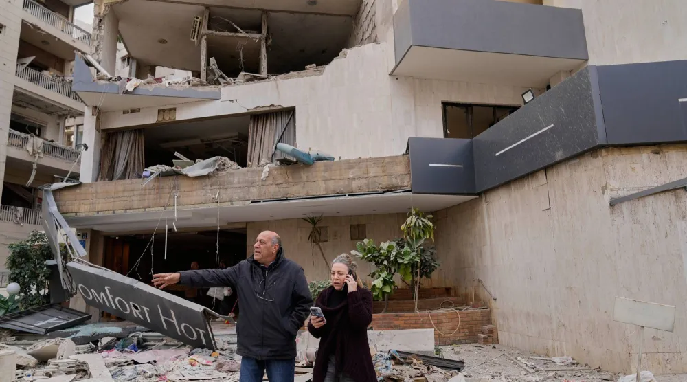 أشخاص يقفون أمام فندق متضرّر جرّاء غارة جوية إسرائيلية استهدفته في منطقة الحازمية شرق بيروت (أ.ب)