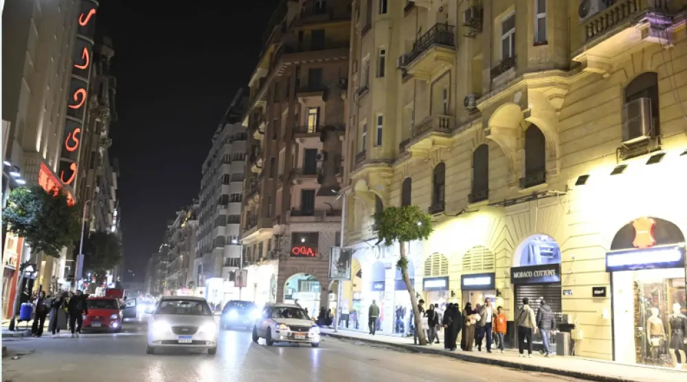 مصريون يسيرون بوسط القاهرة في الشهر الحالي قبل إغلاق المحال التجارية (أ.ف.ب)