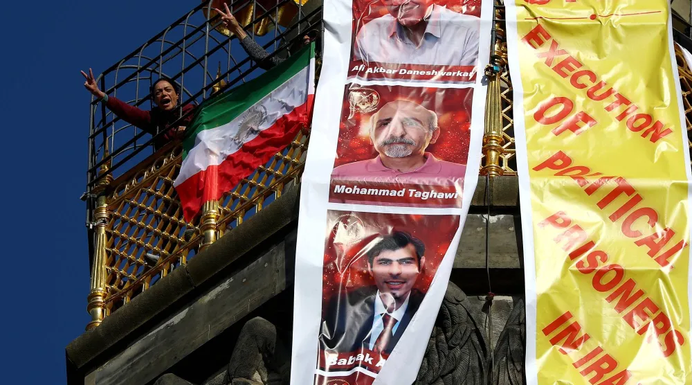 إيرانيون في المنفى يحتجون برفع لافتة كُتب عليها «أوقفوا إعدام السجناء السياسيين في إيران» أعلى عمود النصر في برلين بألمانيا 2 أبريل 2026 (رويترز)