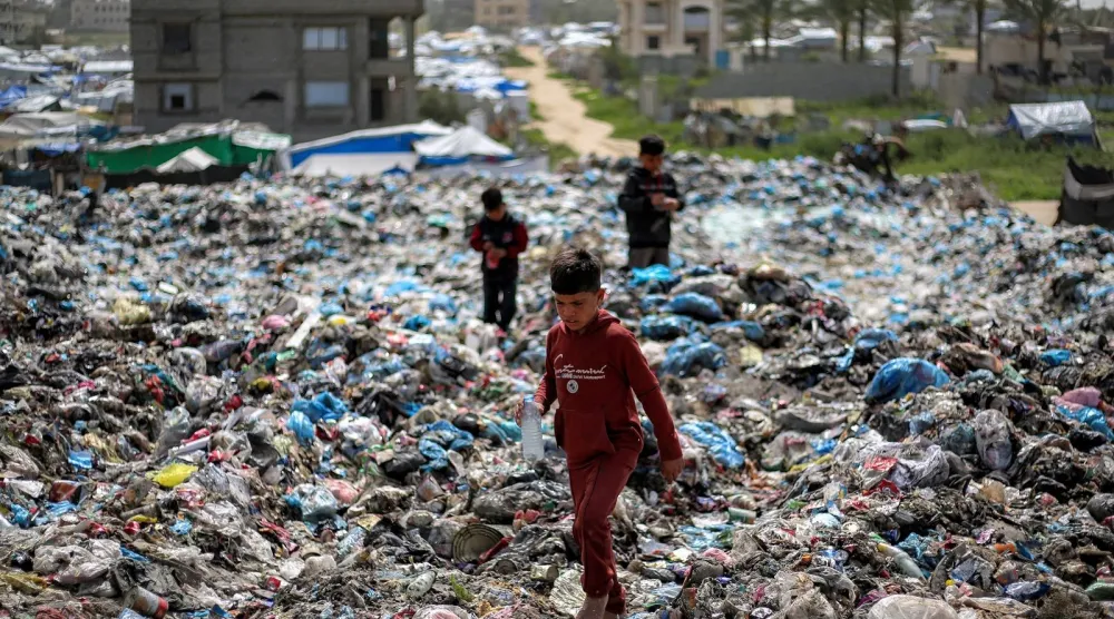 أطفال يبحثون عن مواد قابلة للتدوير في ساحة نفايات بمخيم البريج للاجئين الفلسطينيين بغزة (أ.ف.ب)
