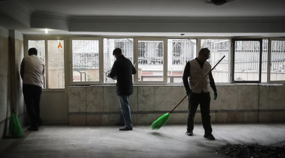 رجال إيرانيون ينظفون شقة داخل مبنى سكني تعرض لغارة جوية في طهران وسط الحرب الأميركية - الإسرائيلية على إيران (د.ب.أ)