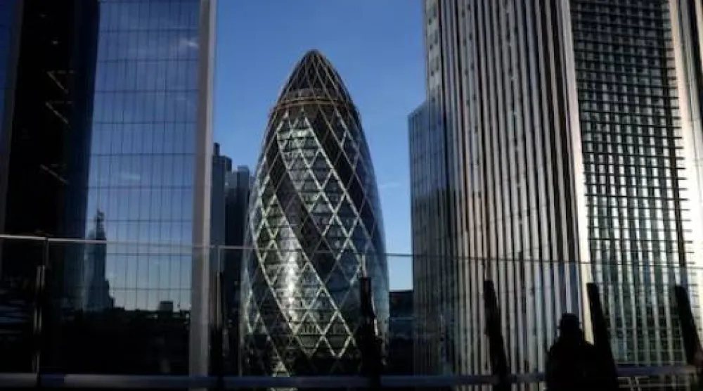 شخص يطل من سطح في منطقة الأعمال بلندن مع برج غيركن في الخلفية (رويترز)