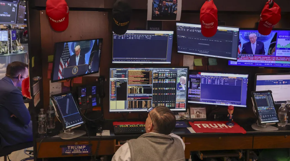 متداول في قاعة بورصة نيويورك بينما تُظهر الشاشة خطاب الرئيس دونالد ترمب خلال مؤتمر صحافي حول الحرب مع إيران (إ.ب.أ)
