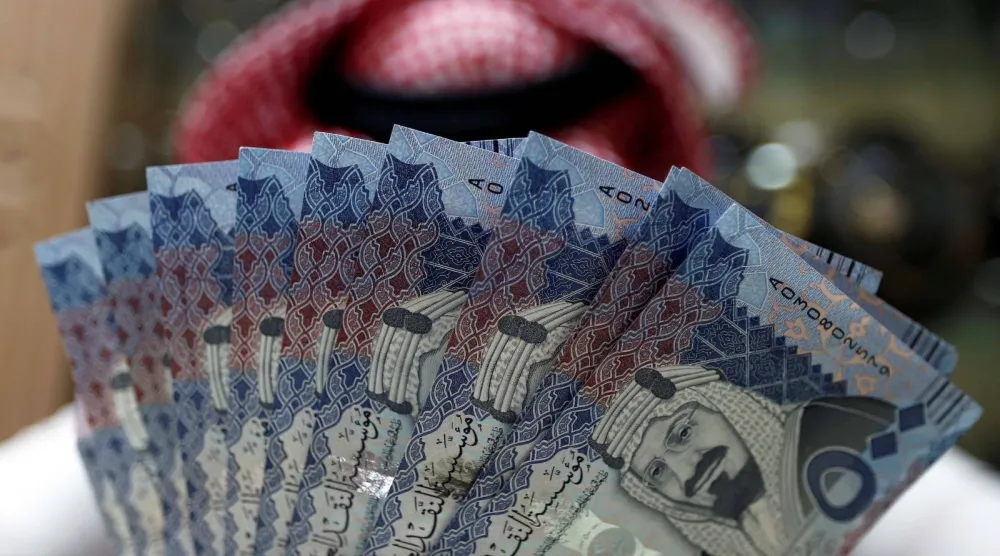 رجل يمسك بأوراق مالية من فئة 500 ريال سعودي (رويترز)