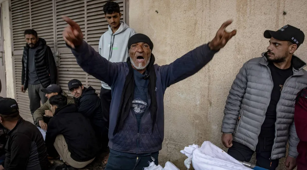فلسطينيون بجوار جثامين ضحايا غارة جوية إسرائيلية في وسط قطاع غزة يوم الثلاثاء (إ.ب.أ)