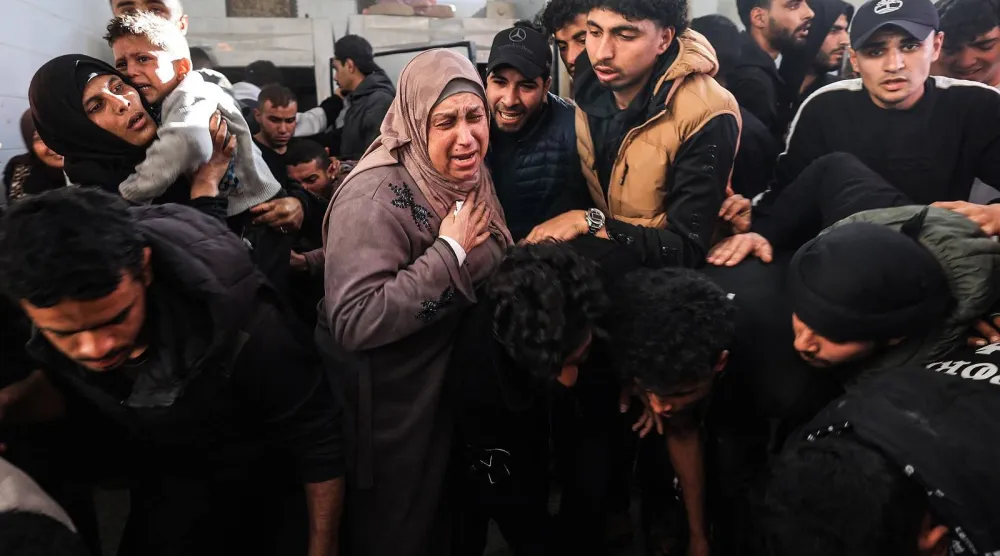 فلسطينيون يبكون خلال تشييع أحد أقاربهم من مستشفى «شهداء الأقصى» في دير البلح يوم الثلاثاء بعد مقتله في غارة إسرائيلية وسط غزة يوم الاثنين (أ.ف.ب)