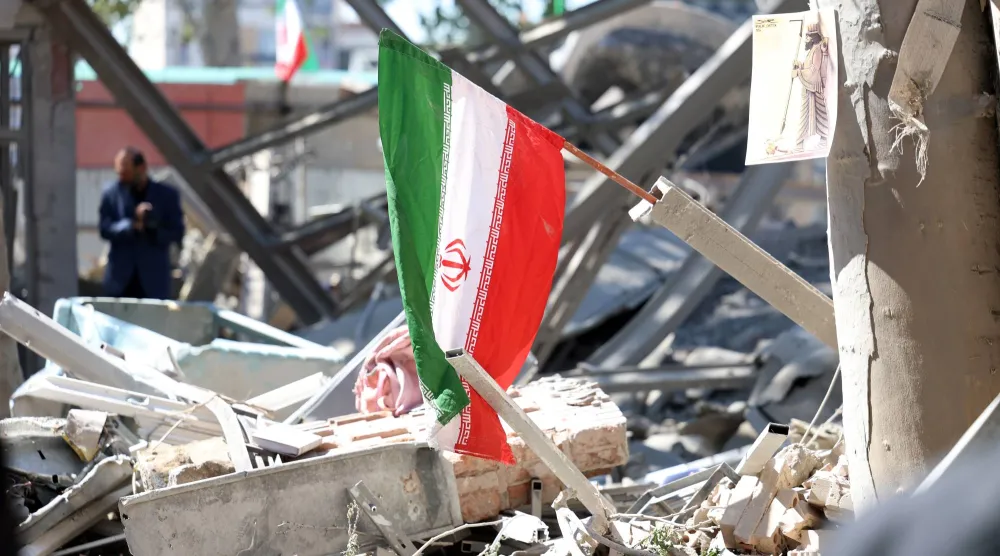 العلم الإيراني يظهر على أنقاض مبنى متضرر في إحدى الجامعات بعد غارة جوية في طهران (إ.ب.أ)