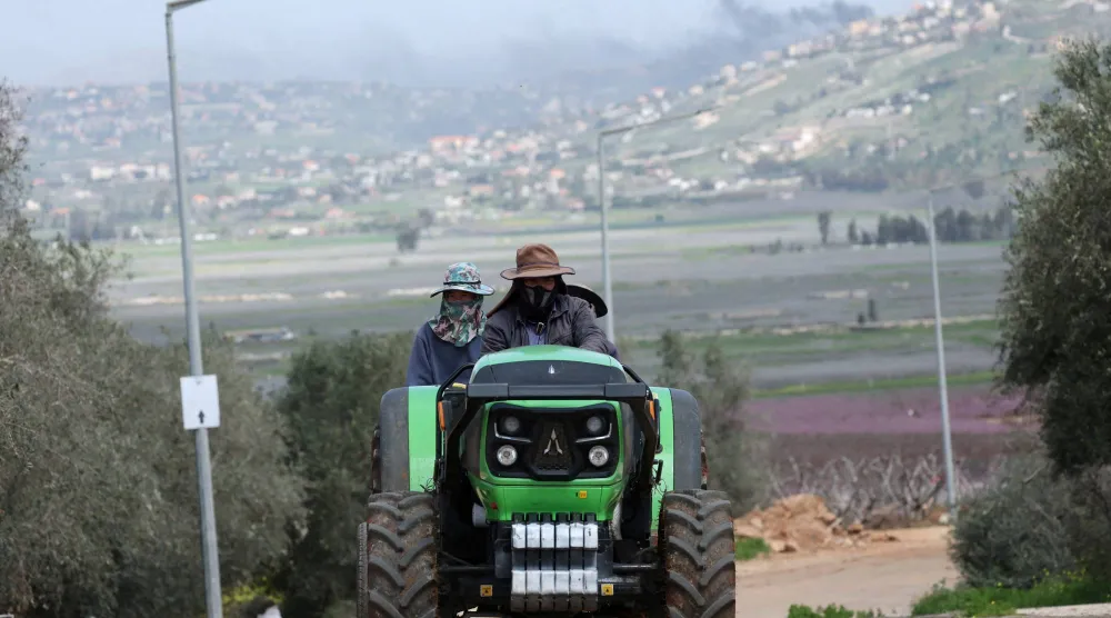 مزارعان محليان يستقلان جراراً على الجانب الإسرائيلي من الحدود مع لبنان وسط تصعيد بين «حزب الله» وإسرائيل (رويترز)