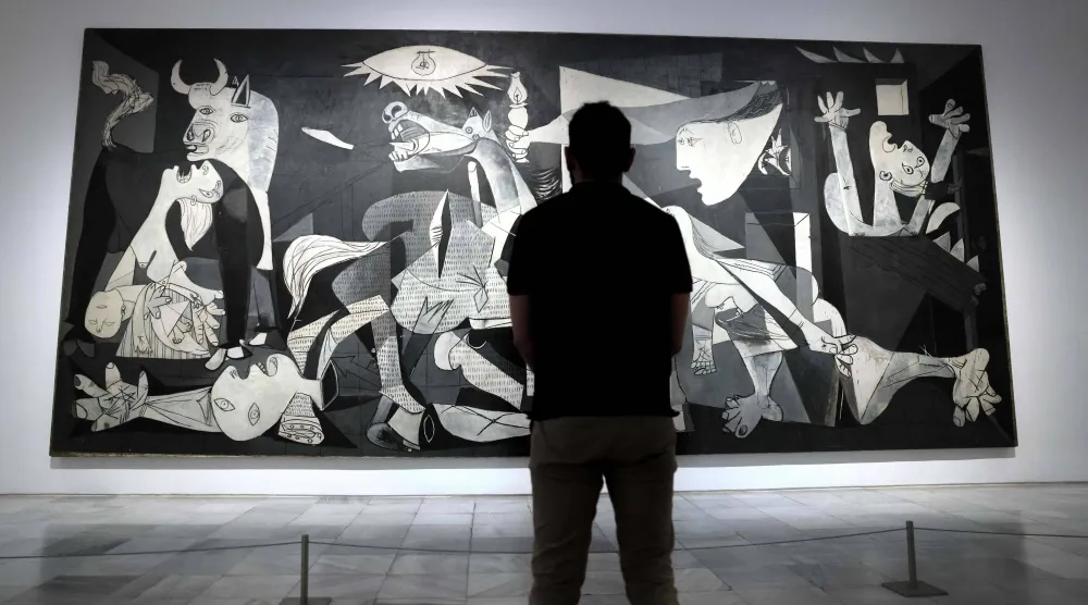 A visitor looks at Spanish painter Pablo Picasso's master piece "Guernica" during a press conference presenting the "Year of Picasso" events, marking the 50th anniversary of the painter's death, at the Reina Sofia museum in Madrid, on September 12, 2022. (Thomas Coex/ AFP)