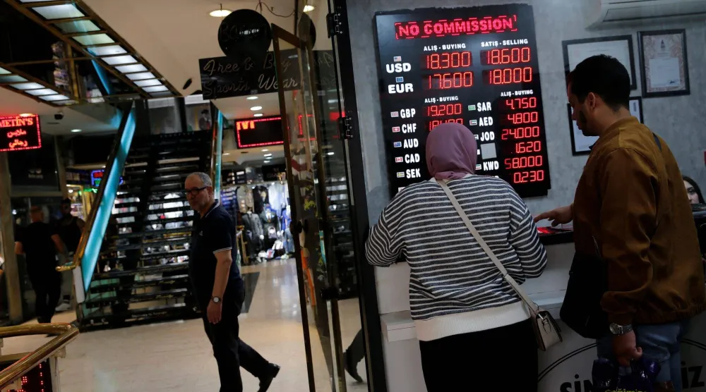 سياح يقفون أمام مكتب صرافة في إسطنبول (رويترز)