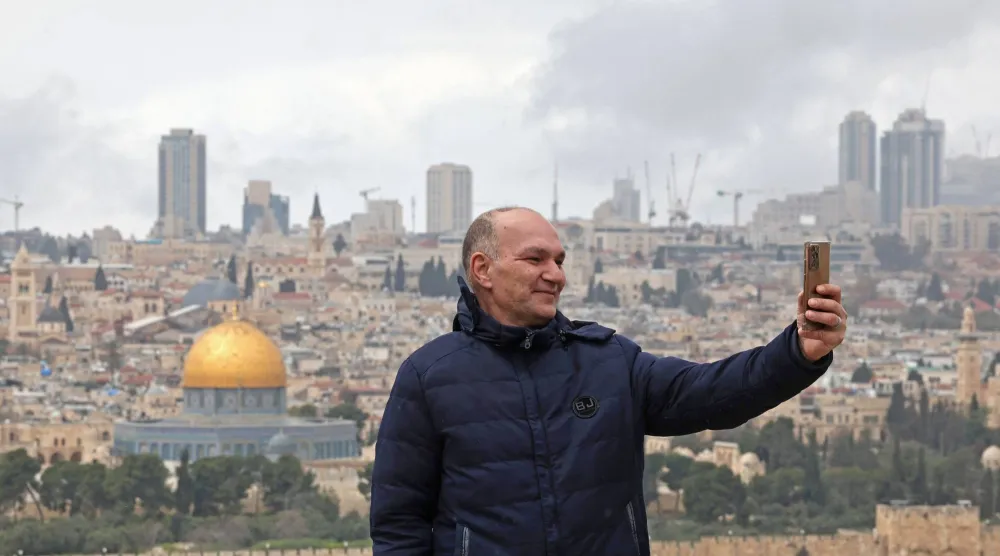 فلسطيني يلتقط صورة سيلفي مع المسجد الأقصى يوم الأربعاء الذي ظل مغلقاً منذ بدء الحرب (أ.ف.ب)