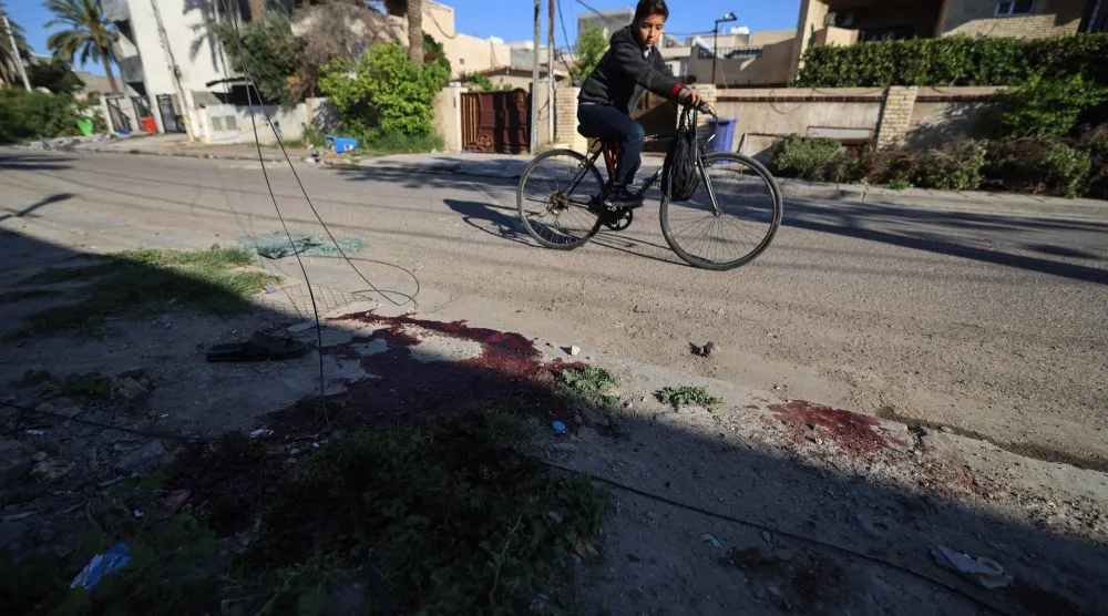 صبيّ يقود دراجة هوائية ويمرّ بجانب بقع دم في موقعٍ تعرّض فيه منزل لدمارٍ جزئي نتيجة مقذوف سقط فجر 8 أبريل 2026 (أ.ف.ب)