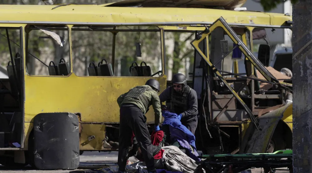 رجال إنقاذ يحملون جثة من الحافلة التي أصابتها مُسيّرة روسية بوسط ​مدينة ‌نيكوبول جنوب شرقي أوكرانيا الثلاثاء (رويترز)