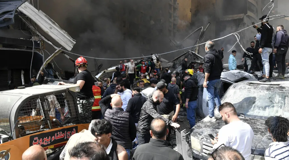 مواطنون يتجمعون أمام مبنى استهدف بغارة إسرائيلية في منطقة كورنيش المزرعة في بيروت (إ.ب.أ) 