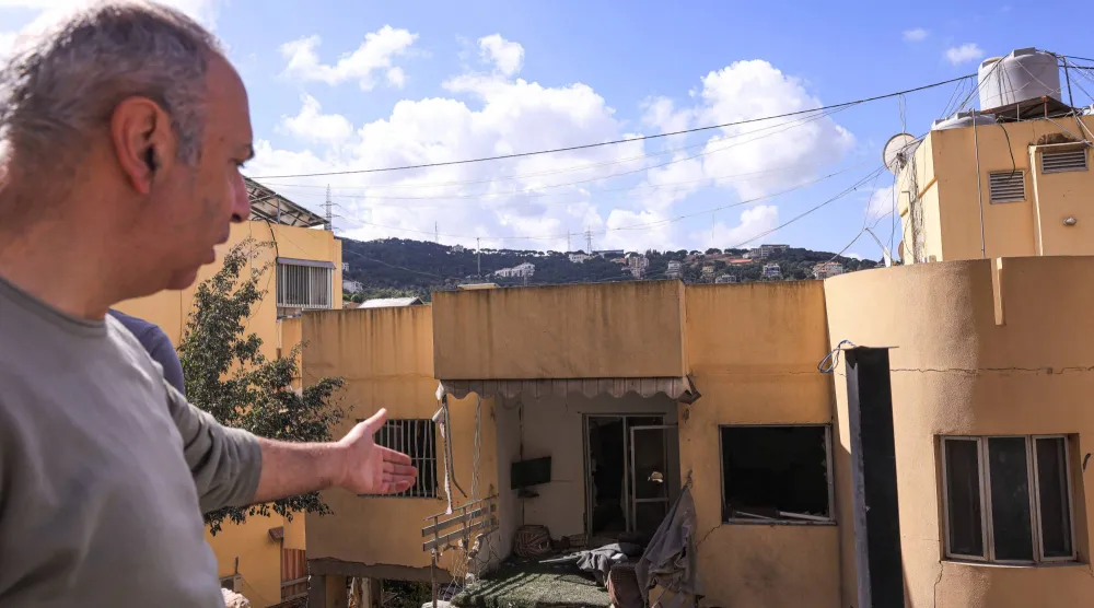أحد السكان المحليين يشير إلى الأضرار التي لحقت بمبنى سكني تعرض لغارة إسرائيلية في عين سعادة بلبنان (رويترز) 