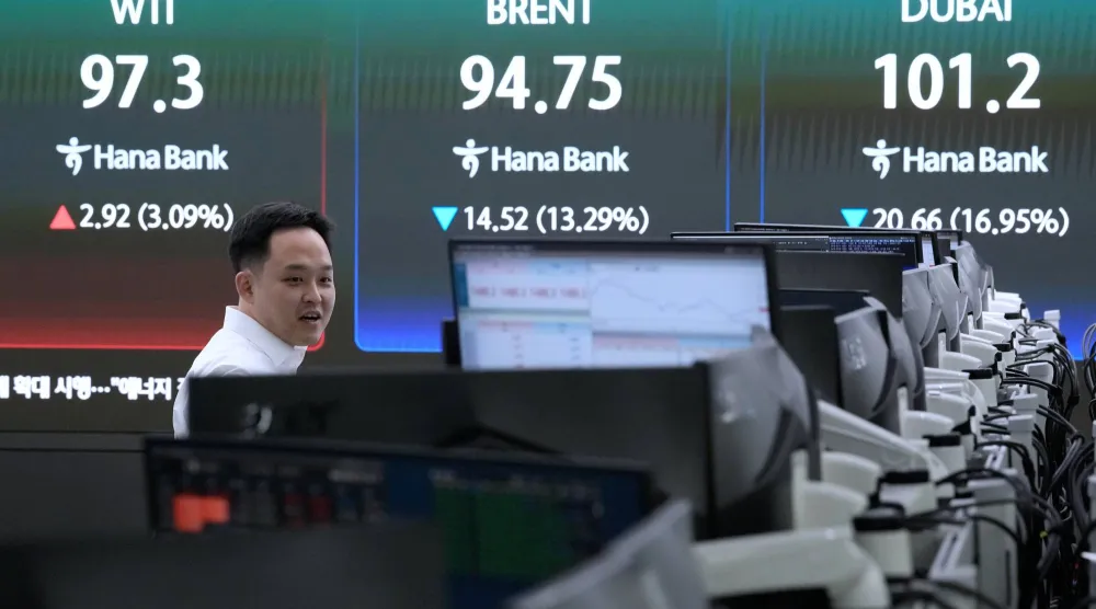 يعمل تاجر عملات بالقرب من شاشة تعرض أسعار النفط في المقر الرئيسي لبنك هانا في سيول (أ.ب)