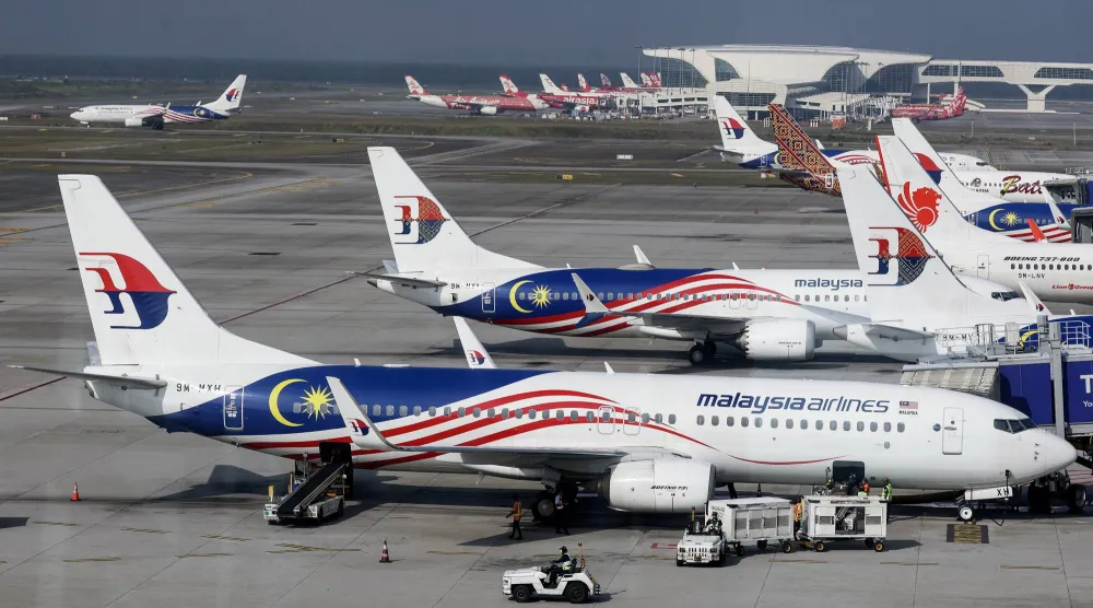 عمال يشحنون البضائع على متن طائرة تابعة لـ«الخطوط الجوية الماليزية» بـ«مطار كوالالمبور الدولي» في سيبانغ (إ.ب.أ)